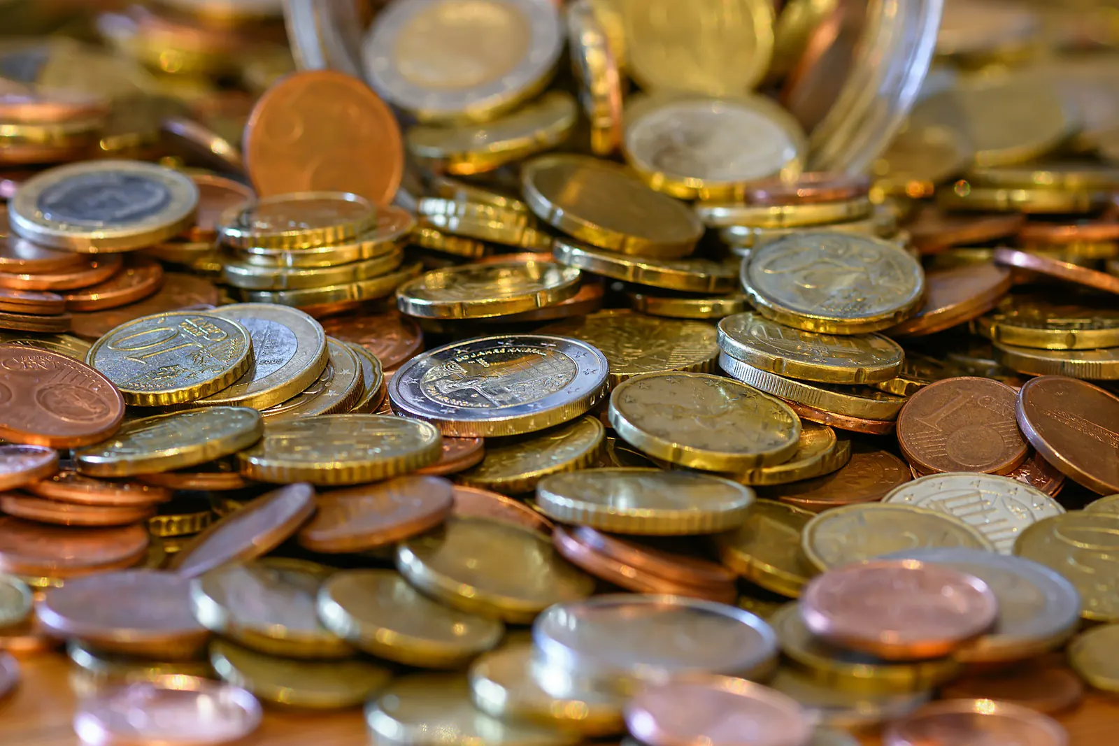 Des pièces de monnaie en euros entassées sur une table en bois, en gros plan. Photo d’illustration.