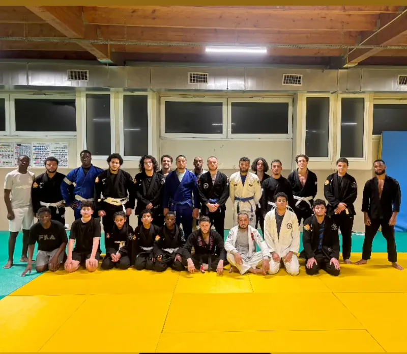 Photo de groupe des pratiquants de La Connexion, en kimono et en tenue de sport, sur le tatami du gymnase